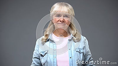 Upset elderly woman looking into camera, difficulties in retirement age, crisis Stock Photo