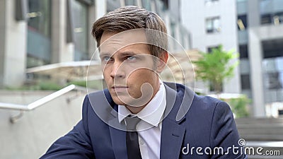 Upset employee sitting on stairs near business center, thinking over problems Stock Photo