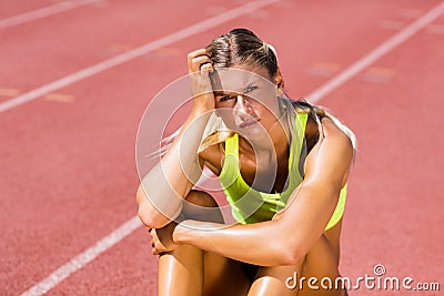 Upset female athlete sitting on running track Stock Photo