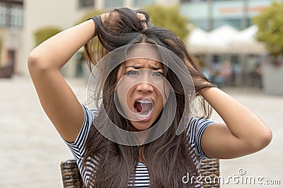 Upset frantic young woman tearing at her hair Stock Photo
