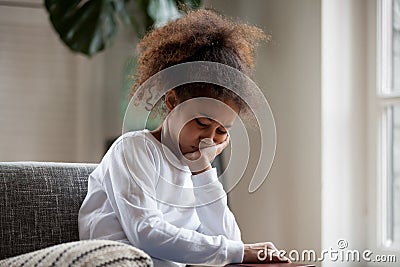 Upset little african girl feeling sad sitting alone at home Stock Photo