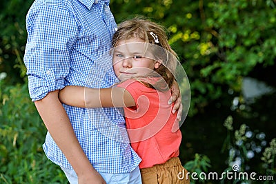 An upset little girl finds comfort in the embrace of her caring teenage brother, exemplifying the bond of a loving Stock Photo