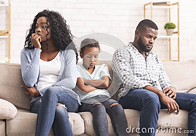 Upset little girl suffer from family conflict, sitting between parents. Stock Photo