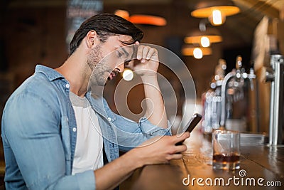 Upset man using mobile at pub Stock Photo