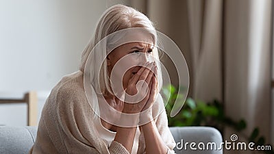 Upset mature woman crying, sitting alone, feeling lonely and unwell Stock Photo