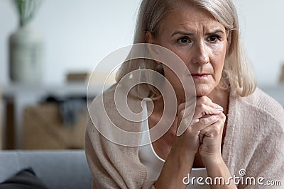 Upset mature woman sitting alone, thinking, feeling unwell Stock Photo