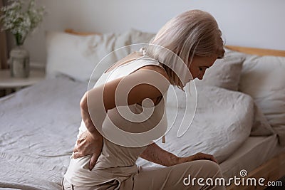 Upset mature woman suffering from backache, rubbing stiff muscles Stock Photo