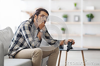 Upset middle-eastern guy got bored while playing video games Stock Photo