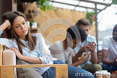 Upset offended girl feel lonely sit alone apart of friends Stock Photo