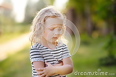 Upset or offended little girl standing on street of small town`s or village`s. Ð¡risis of three years Stock Photo