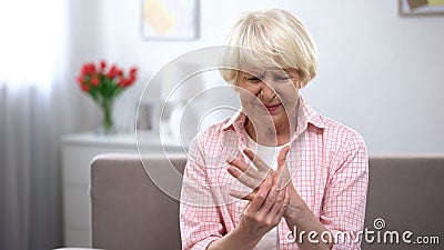 Upset old woman suddenly feeling sharp pain in wrist, arthritis health problem Stock Photo