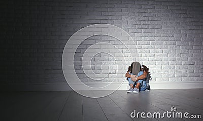 Upset sad sad child girl in stress cries at an empty dark wall Stock Photo