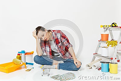 Upset sad woman holds bundle of cash money, supermarket grocery push cart for shopping. Instruments for renovation Stock Photo