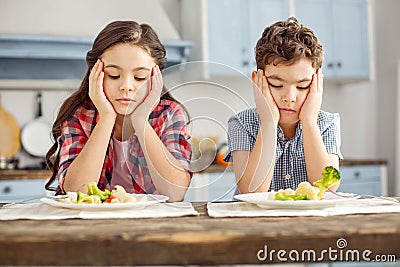 Upset siblings looking sadly at the vegetables Stock Photo