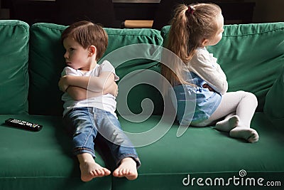 Upset siblings sitting on sofa ignoring each other after fight Stock Photo