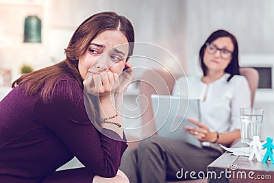 Upset sorrowful brown-haired woman crying while visiting a phycologist Stock Photo