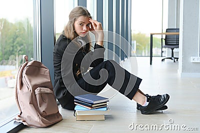 Upset teen girl sit on floor sadly look out window worried about teenage problem at school and communication with parent Stock Photo