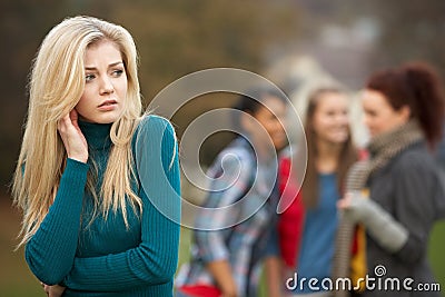 Upset Teenage Girl With Friends Gossiping Stock Photo