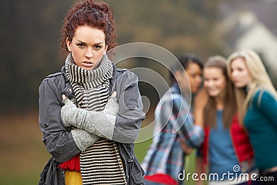 Upset Teenage Girl With Friends Gossiping Stock Photo