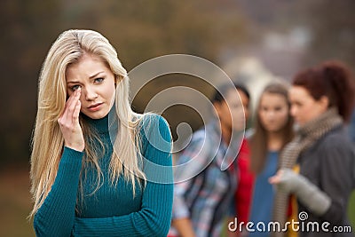 Upset Teenage Girl With Friends Gossiping Stock Photo