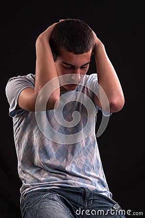 Upset teenager with head in hands wincing from stress, anguish o Stock Photo