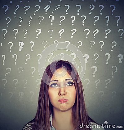 Upset thinking woman looking up many question marks above head Stock Photo