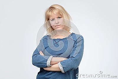 Upset unsatisfied blonde woman standing with arms folded Stock Photo