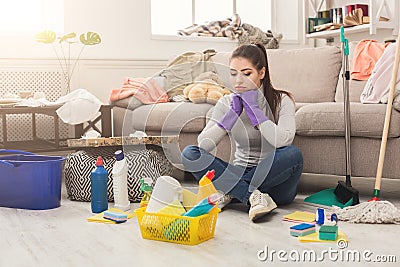 Upset woman cleaning house with lots of tools Stock Photo