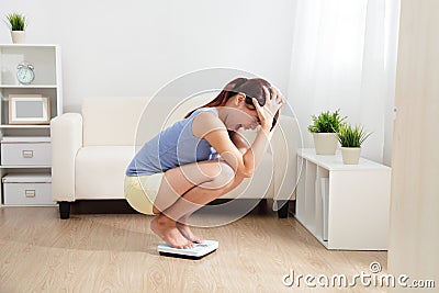 Upset woman on weigh scale Stock Photo