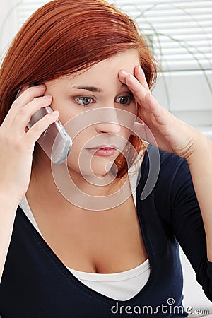 Upset and worried young woman talking by phone Stock Photo