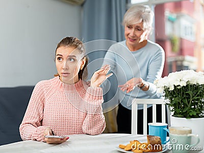 Worried elderly mother reprimanding upset girl at table Stock Photo