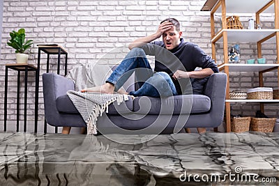 Upset Man In The Room Flooded With Water Stock Photo