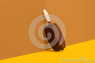 Chocolate dipped ice lolly on a brown and yellow background Stock Photo