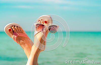 Upside woman feet and red pedicure wearing pink sandals, sunglasses at seaside. Funny and happy fashion young woman relax Stock Photo