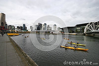 Kayak paddlers on Yarra River, South Wharf, Melbourne, Victoria, Australia. Promenade with coastal cityscape of skyscrapers Editorial Stock Photo