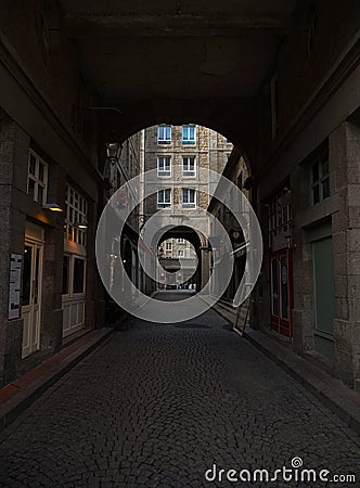 Urban cityscape view of stone gate arch architecture in empty narrow cobblestone street of Saint Malo Brittany France Editorial Stock Photo