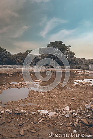 Urban demolition construction site area with waste concrete stone and dirty pond in the sunset time with aqua blue sky. Stock Photo