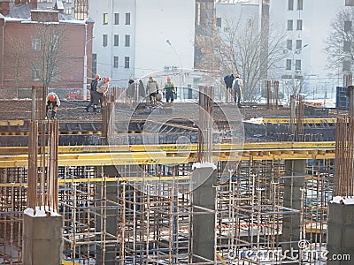 Urban development. construction site in winter during the day. workers in uniform prepare the scaffolding Editorial Stock Photo
