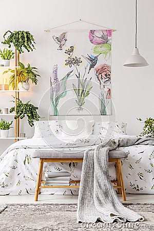 Urban jungle bedroom interior with a bed dressed in white and green bedding and painted art on the wall Stock Photo