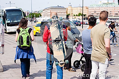 Urban life. Tourists with backpack and longboard outdoors Editorial Stock Photo