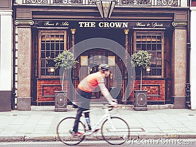 Urban scene of a cyclist walking in front of an English pub Editorial Stock Photo