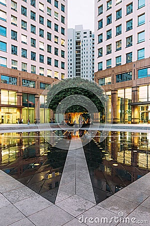 Urban space fountain area with big green tree in the corner with people. This area amid modern office buildings left and right. Editorial Stock Photo