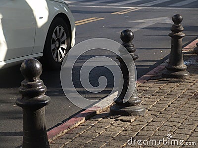 Urban street view of a white car driving on the road with a diagonal composition and view of the sidewalk in daylight Stock Photo