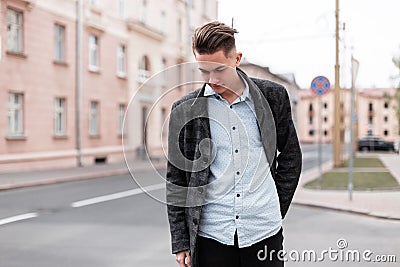 Urban stylish young guy with trendy hairstyle in fashionable elegant clothes near vintage houses outdoors. Business guy travels Stock Photo