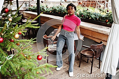 Urban young african american woman in pink top and grey jeans and sunglasses with handbag. Afro fashion chic women Stock Photo