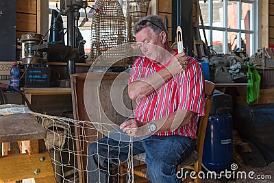 Man in traditional Dutch costume mending fishing nets in workshop Editorial Stock Photo