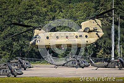 US Army Boeing CH-47F Chinook transport helicopter taking off with UH-60 Blackhawk helicopters in the background. The Netherlands Editorial Stock Photo