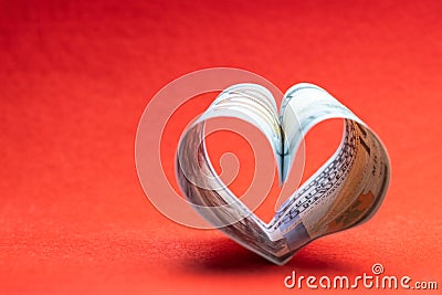 US 100 dollar bill in the shape of a heart on a red background. Copy space. Concept of money, love and a gift for Stock Photo