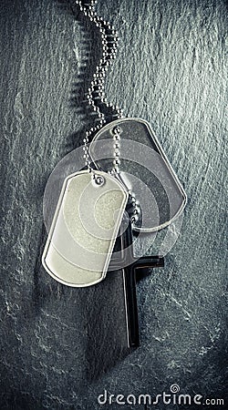 US military soldiers dog tags, rough and worn with blank space for text, and Christian cross necklace. Memorial Day or Veterans Stock Photo