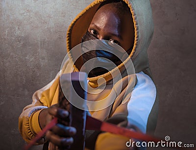 USA anti racist riots - young furious and angry black African American woman in mask and hoodie shooting brick during street riot Stock Photo